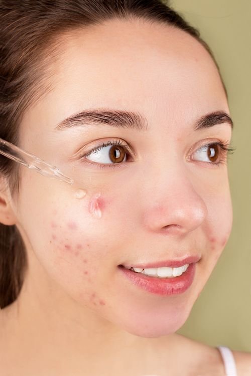 Woman applying facial serum with a dropper during her nighttime skincare routine
