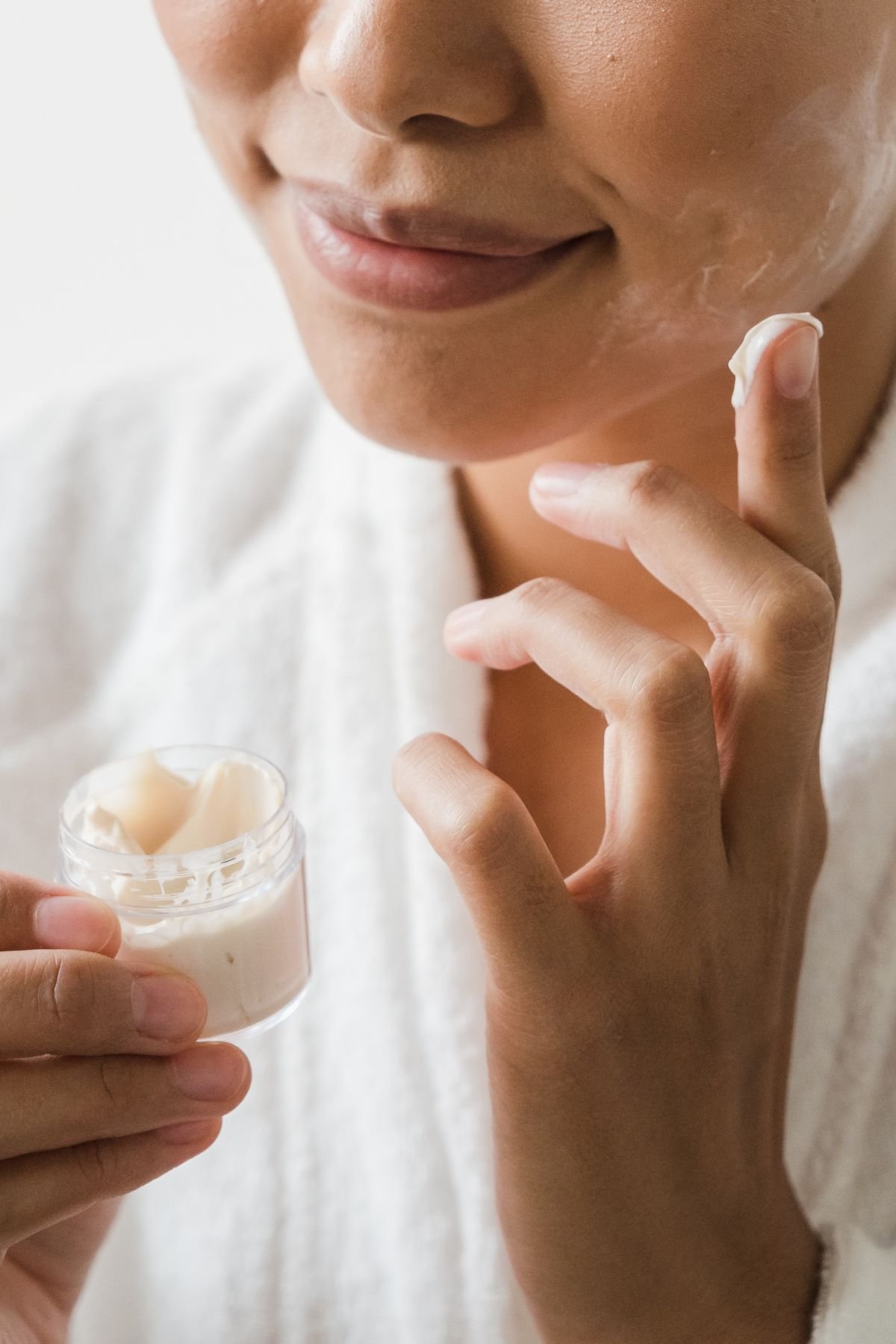 Close-up of fingertips applying facial cream to skin