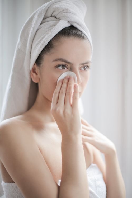 Woman gently wiping her face with a cotton pad during her skincare routine