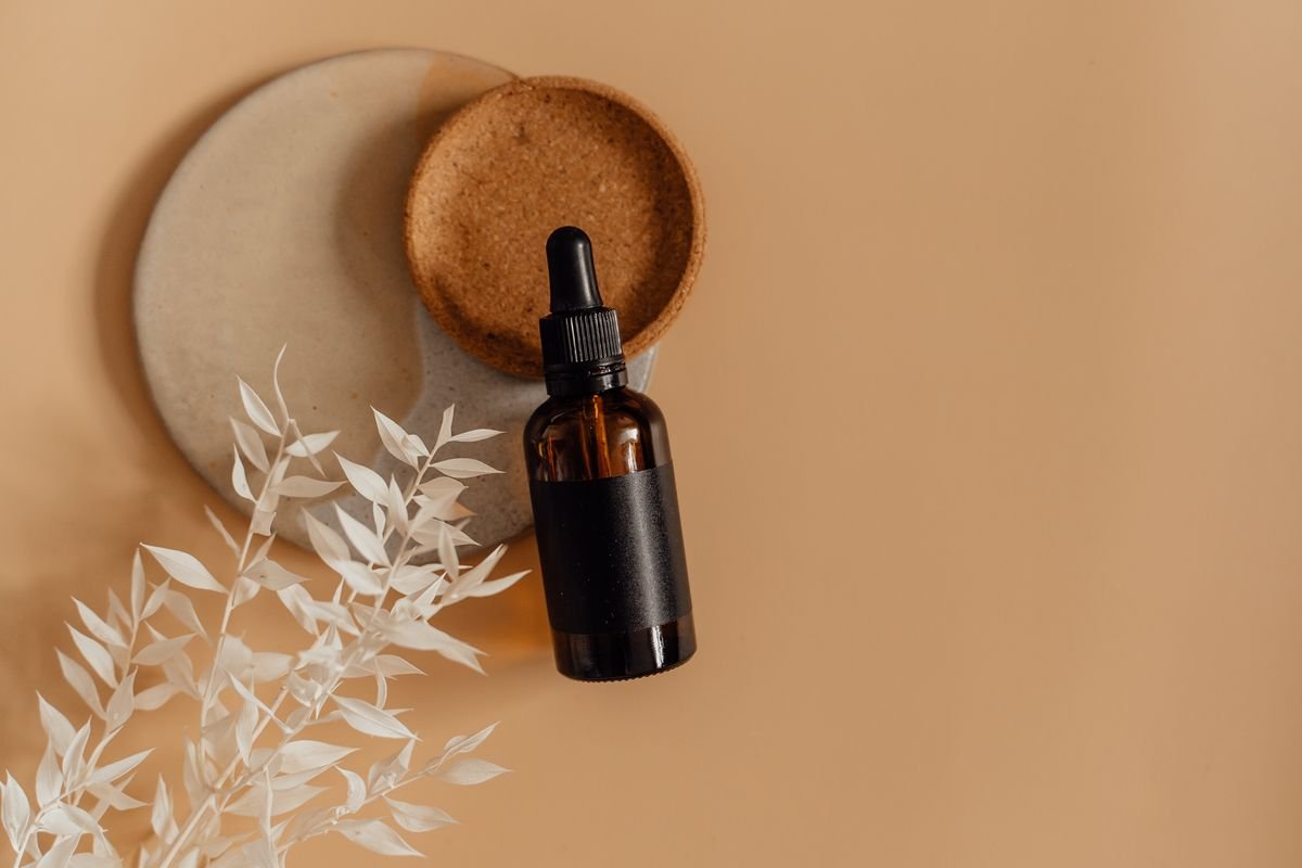 Flatlay of minimalist skincare products including a serum bottle and dropper on a clean surface