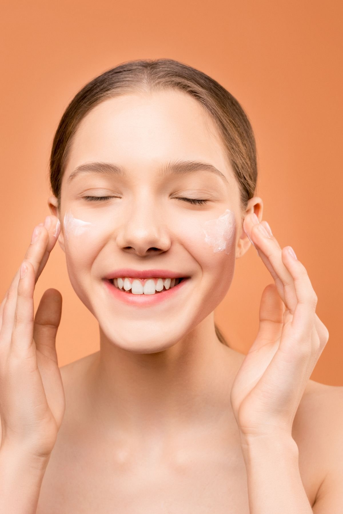 A woman applying face moisturizer as part of her skincare routine